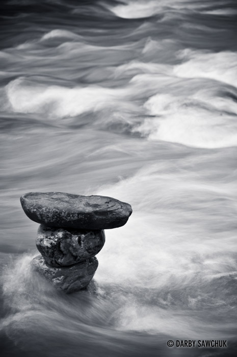 Stones balance in the current of a river in the Rocky Mountains.