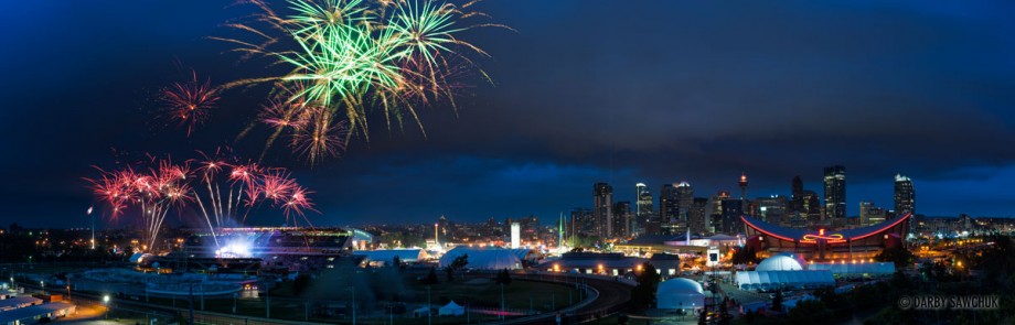 A panoramic view of fireworks exploding over the Calgary Stampede Grounds during the finale of the Grandstand show with the Calgary City skyline on the right.
