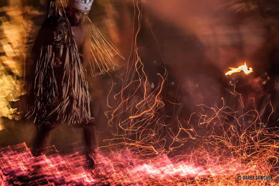 A man carries a wooden horse through burning embers as part of a Kecak dance in Bali.
