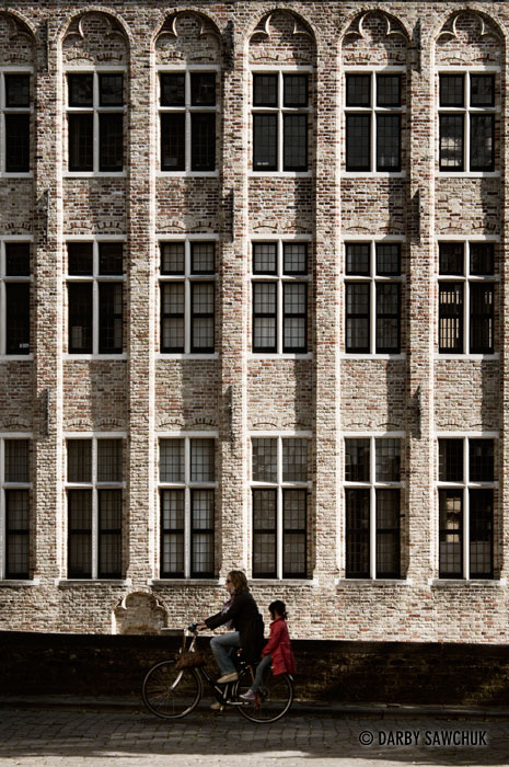 A mother and daughter ride their bike near the Gouden Handrei canal in Bruges, Belgium.