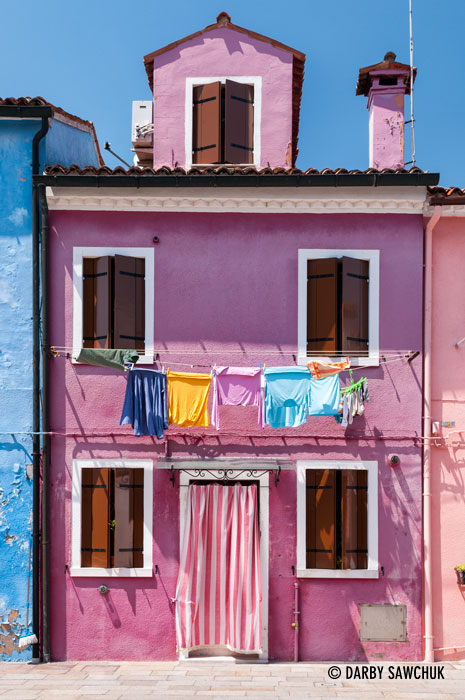 A bright pink house with laundry hung out to dry in Burano, Italy.