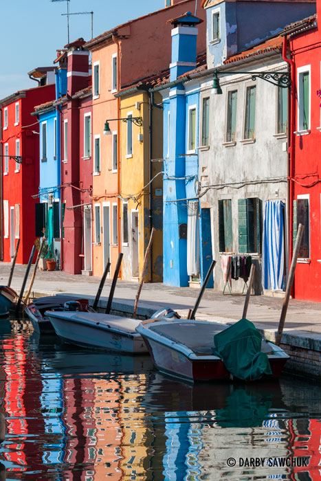 The brilliant colours of the houses are reflected in the waters of the canals in Burano, Italy.