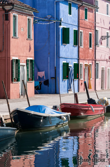 The brilliant colours of the houses are reflected in the waters of the canals in Burano, Italy.
