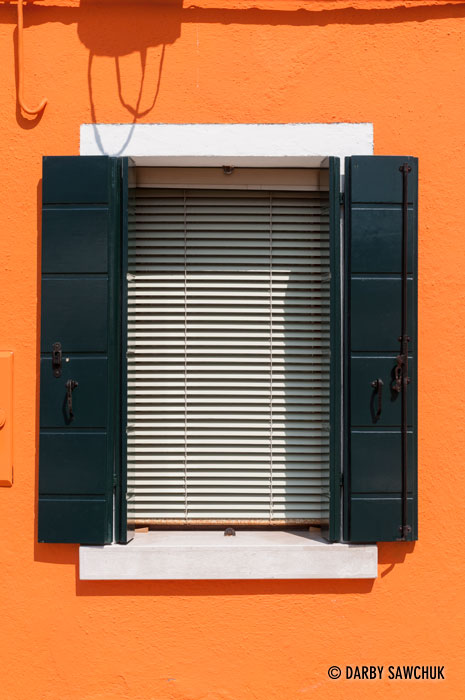 The window of a bright orange house in Burano, Italy.