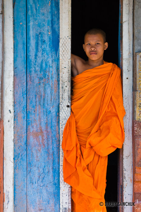 A novice Buddhist monk stands in a doorway at Bakong Monastery outside Bakong temple near Angkor Wat in Cambodia.