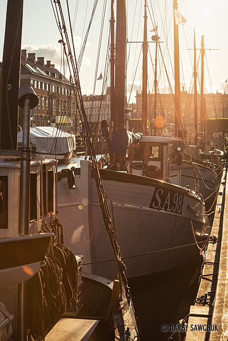 The sun sets over boats moored in the Copenhagen's Nyhavn Canal.
