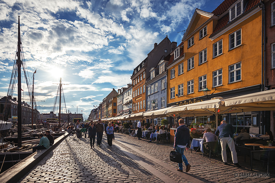 Tourists enjoy they late afternoon sun along the banks of the Nyhavn Canal in Copenhagen, Denmark.