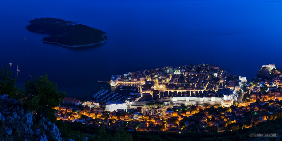 A panoramic view of Dubrovnik's old town and Lokrum island at dusk.