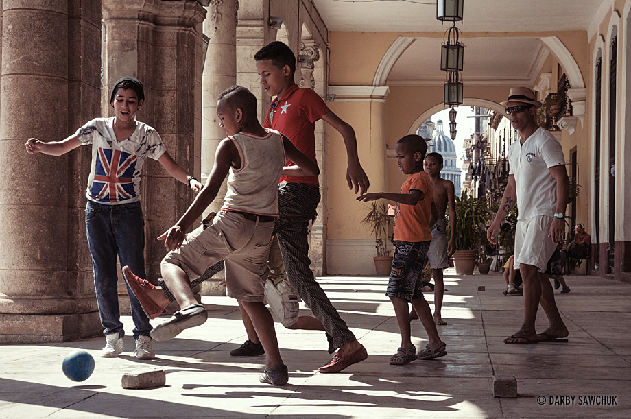 Young boys and teens play football beneath a colonial arcade in the Plaza Vieja in Havana's old town.