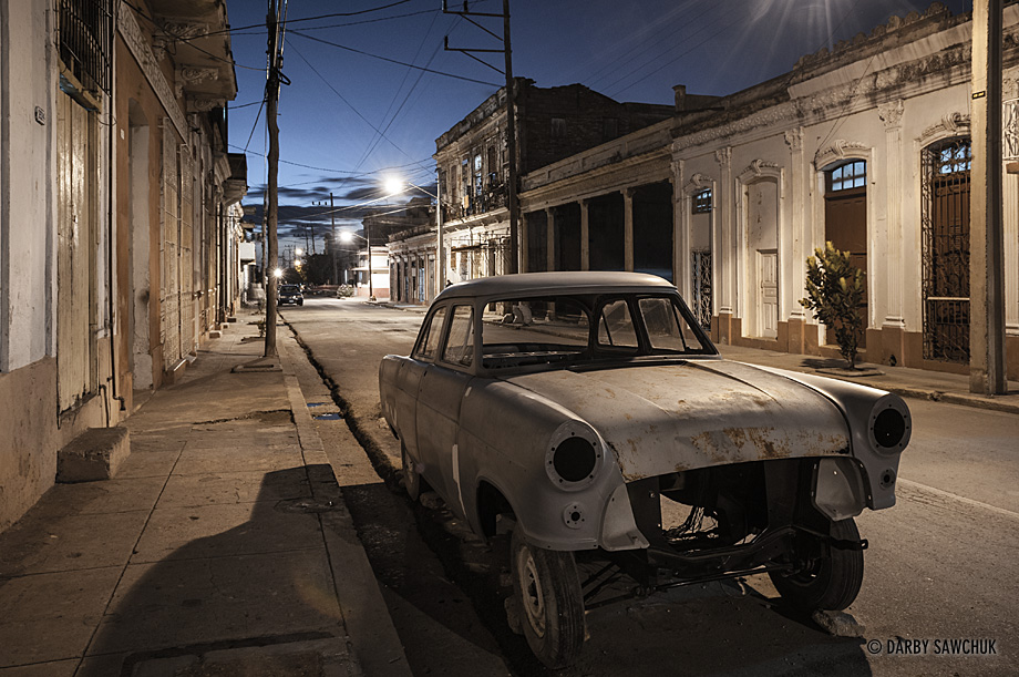 A dismantled classic American car in the streets of Cienfuegos at night.