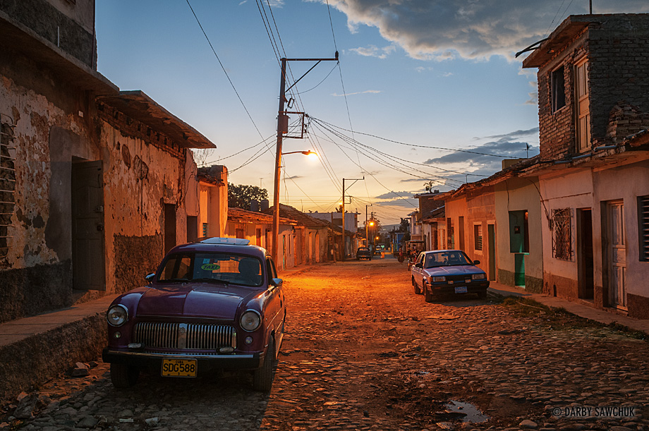Cars in the streets of Trinindad, Cuba at dusk.