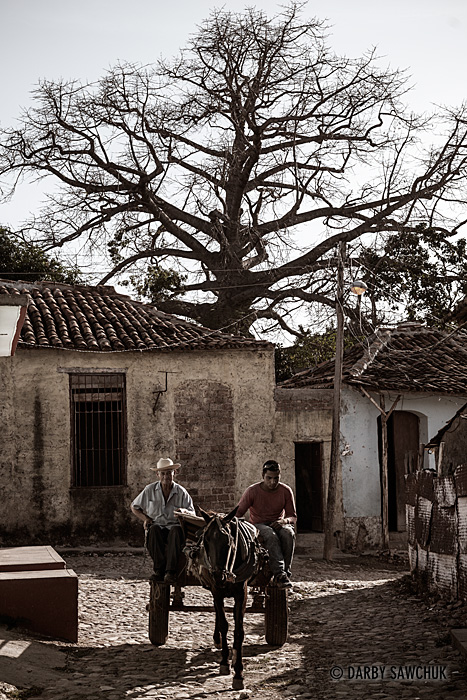 Cuban men lead a horse and cart up a street in Trinindad, Cuba.