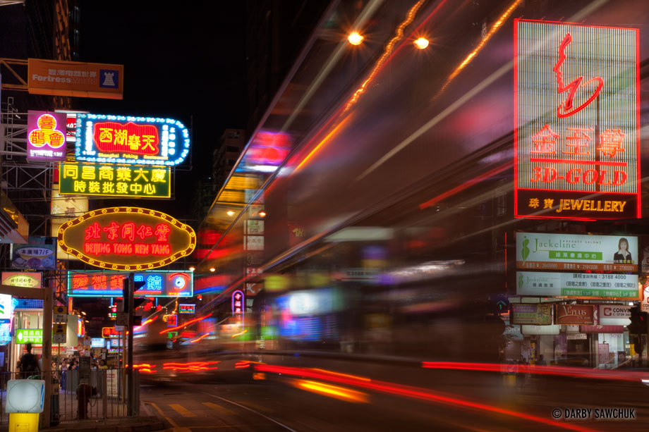 Traffic speeds past the bright neon signs on Nathan Road, the main road in Kowloon.