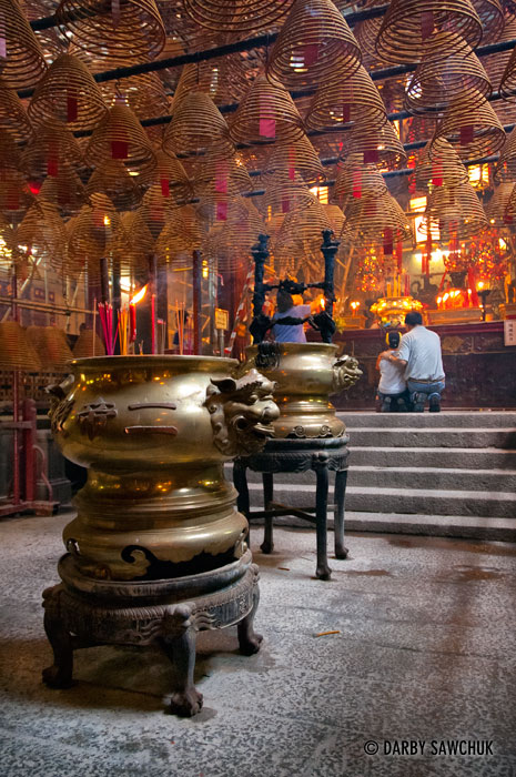 Worshippers pray at the Man Mo Temple where spiralled incense sticks hang from the ceiling.