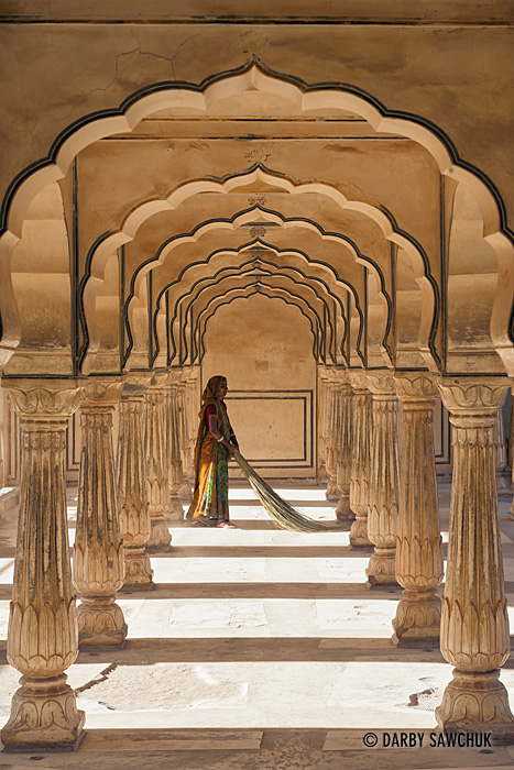 A woman sweeps beneath archways in the Amber Fort near Jaipur, India.