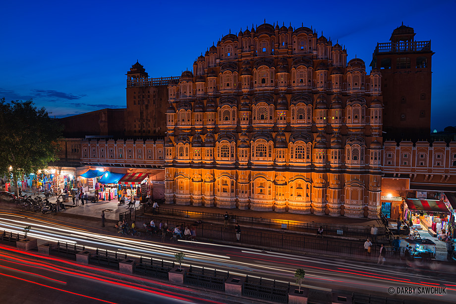Jaipur traffic speeds past the Hawa Mahal, the Palace of Winds at dusk.