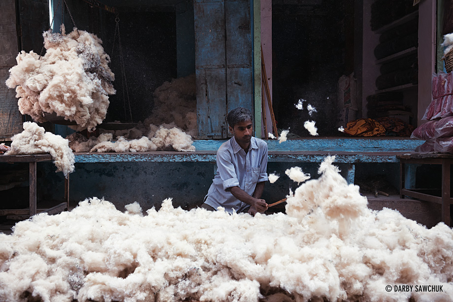 A man fluffs cotton to bundle into mattresses on the streets of Bundi.