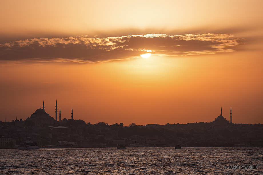 Evening sun silhouettes mosques piercing the Istanbul horizon across the Bosphorus Strait.