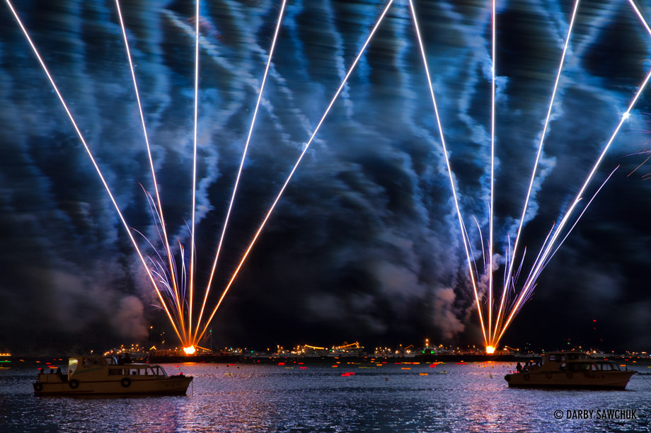 Fireworks burst from the ocean behind boats in the harbor during the Matsushima lantern festival in Miyagi prefecture Japan.