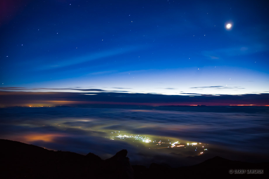 Villages shine their lights through the clouds at dawn from the top of Mount Iwate (Iwate-san) in Northern Japan.