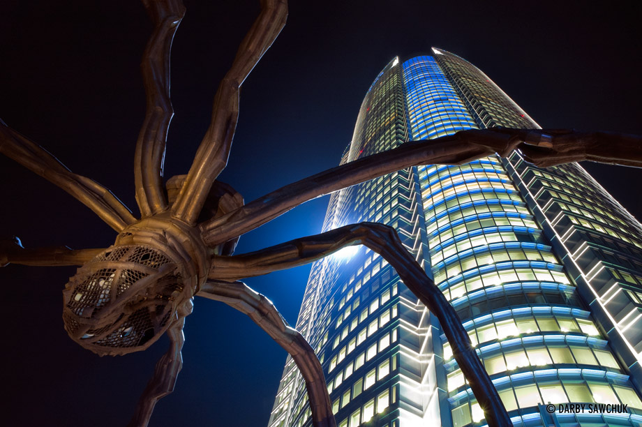 The Mori Tower stands over a sculpture of a spider in the center of the Roppongi Hills complex in Tokyo, Japan.