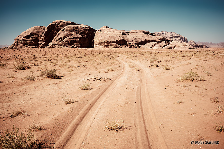 Jeep tracks lead through the sands of Wadi Rum towards one of its many rock sandstone hills.