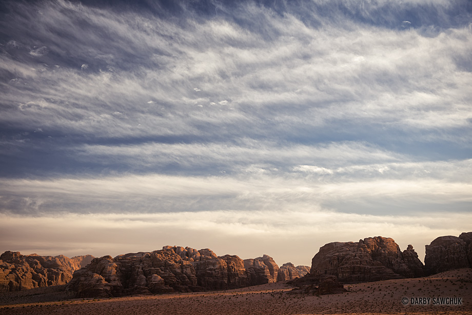 Clouds streak the sky over the rock formations of Wadi Rum, Jordan.