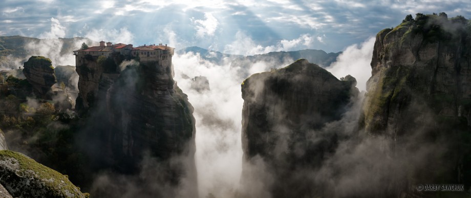 A panoramic photo of the Monastery of Varlaam above the clouds in Meteora, Greece.