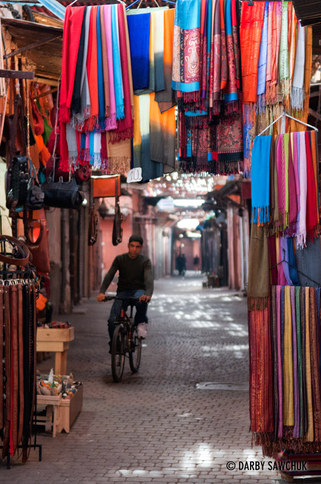 A man rides a bicycle through one of Marrach's souks.