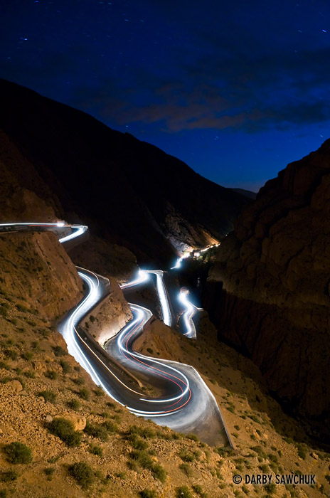 Cars leave light trails as they travel on the winding roads of the Dades Gorge at night.