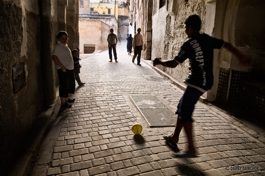 Children play football in a narrow alley in the Fez medina.