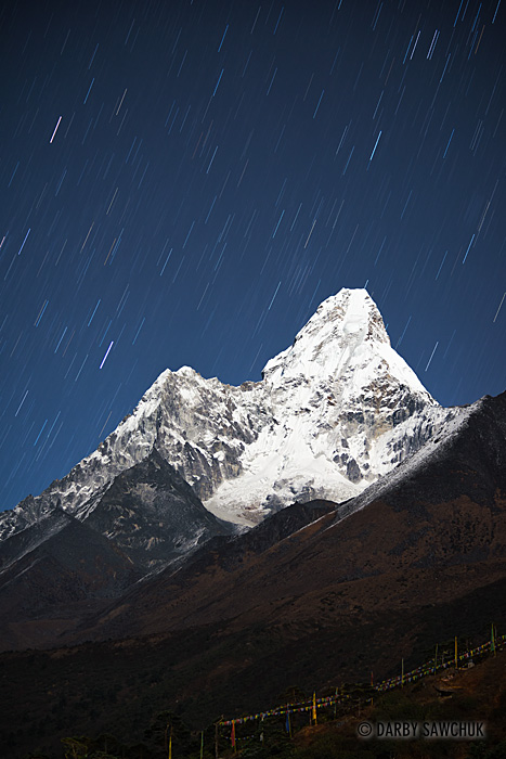 A clear night in the high mountain air of the Himalayas reveals bright stars behind a moonlit Ama Dablam, one of the mountains along the Everest trail in Nepal.