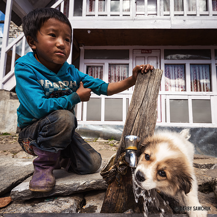 A boy supplies a drink to his puppy in the mountain village of Phakding stationed along the Everest Trail in Nepal.
