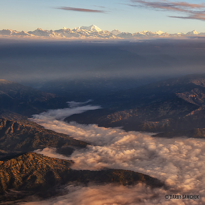 Early morning clouds flow through hills at the base of the Himalayas near Kathmandu.