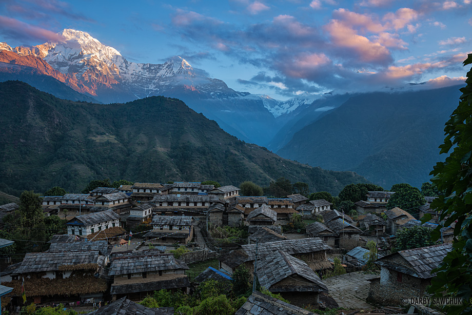 Dawn light hits the mountains of the Annapurna range behind the medieval village of Ghandruk, Nepal.