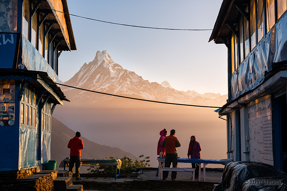 The first light of day hits Mount Machhapuchchhre (also known as Fish's Tail) as viewed from between the guesthouses in Tadapani, Nepal.