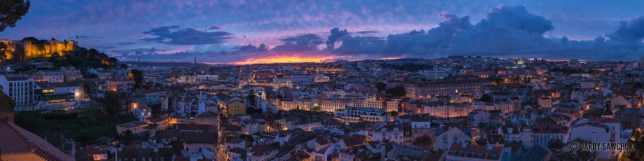 A panoramic view of Lisbon from the Miraduro de Graca during the blue hour of dusk.