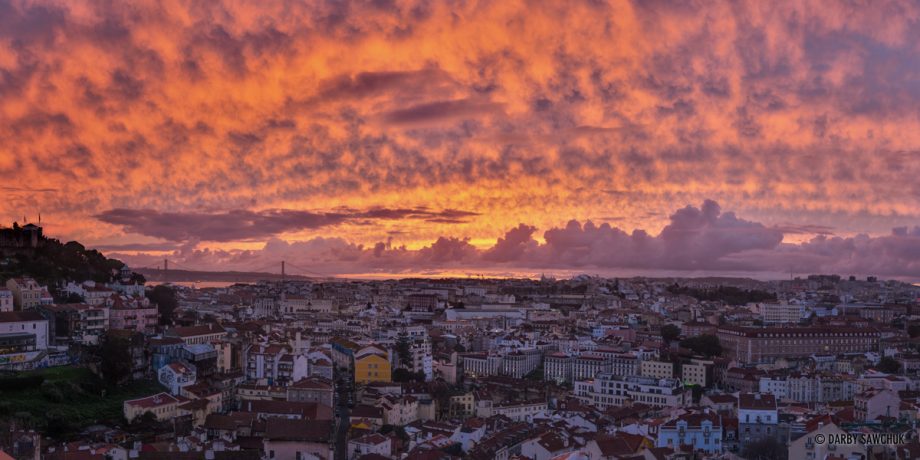 A panoramic view of Lisbon from the Miraduro de Graca during a vibrant sunset.