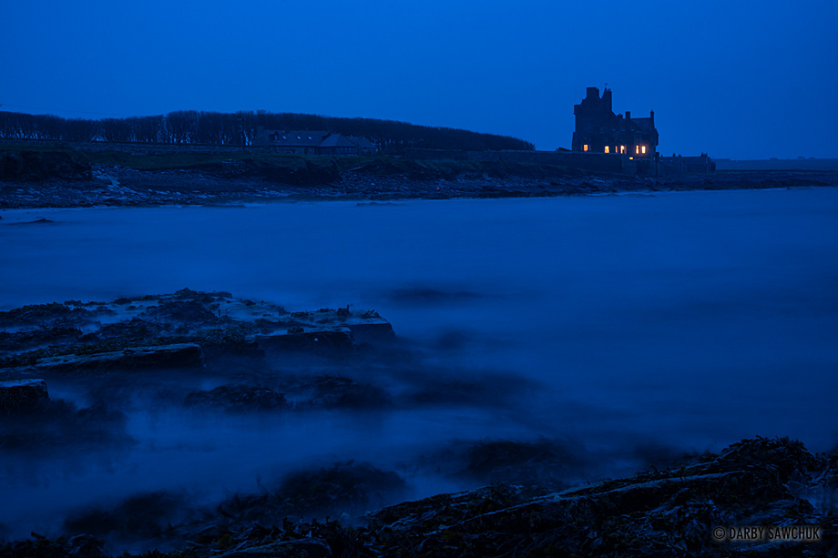 Ackergill Tower at dusk on Sinclair's Bay in the north of Scotland.