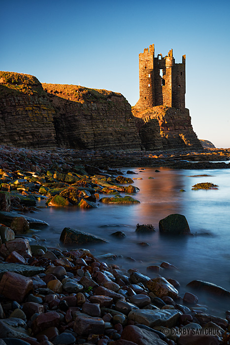 The ruin of Old Keiss Castle balances precariously on a cliff on the coast of Caithness, Scotland.