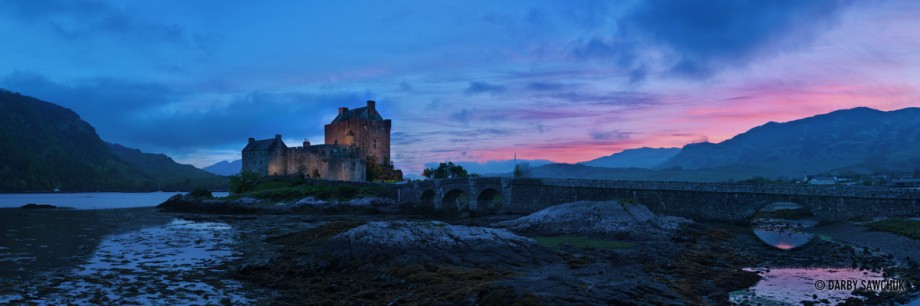 A panoramic view of Eilean Donan Castle at dusk in Scotland.