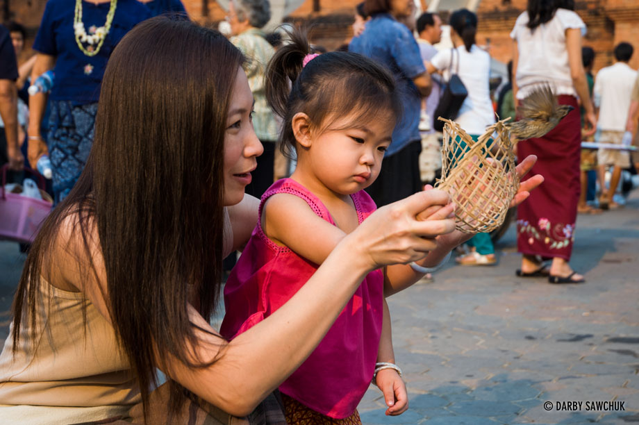 A mother and daughter release birds from a cage to gain good luck in Chiang Mai, Thailand during Songkran.