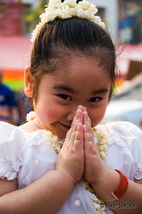 A young Thai girl makes a symbol of greeting called a wai.