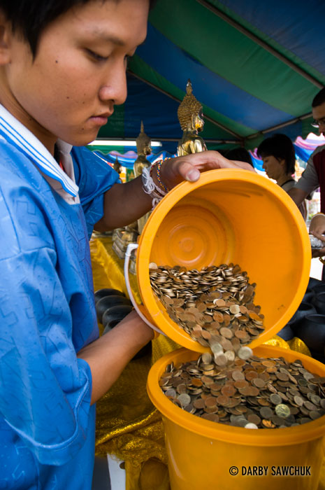 A man attends to coins offered by worshippers at Phra Singh temple in Chiang Mai, Thailand during Songkran.