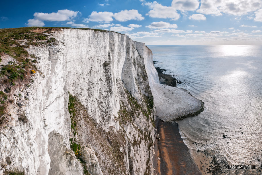 The striking chalk faces of the White Cliffs of Dover. A recent landslide is visible jutting into the ocean.