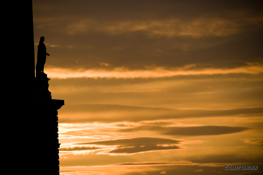 A sculpture on the edge of the Royal Palace of Madrid looks out to the sunset.