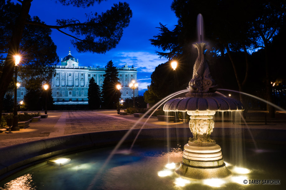 A fountain in front of the Royal Palace of Madrid in the evening.