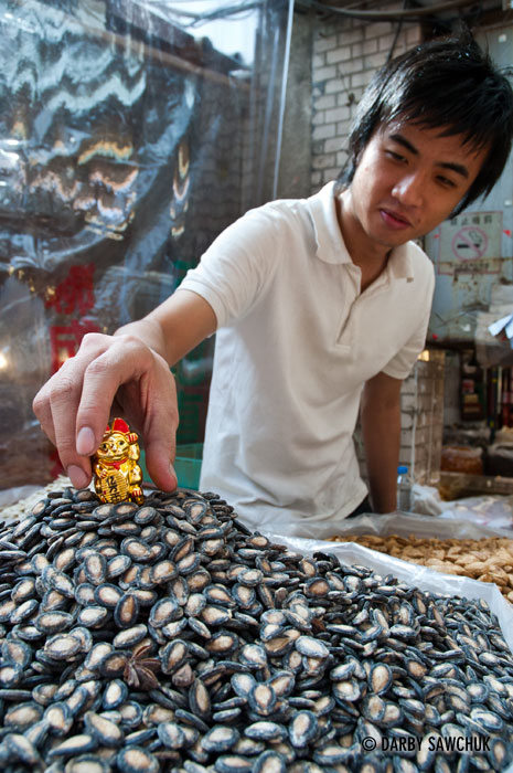 A vendor placing a lucky cat charm on his sundries at Dihua Street Market in Taipei, Taiwan.