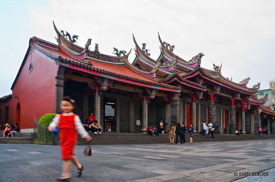 A young girl walks past the front entrance of Xingtian Temple in Taipei, Taiwan.