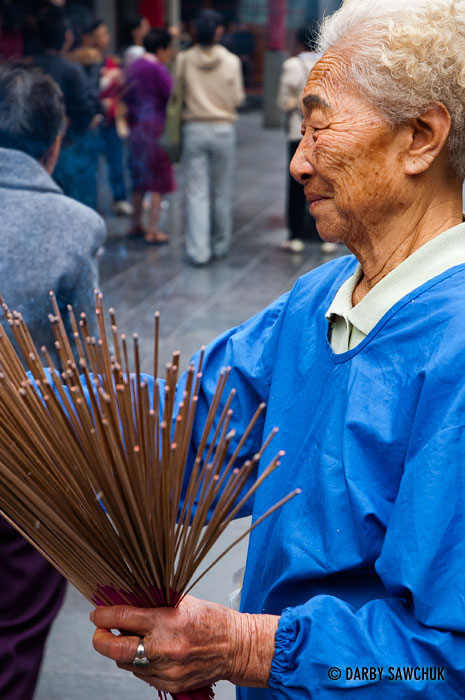 An elderly woman hands out incense sticks at Xingtian Temple in Taipei, Taiwan.